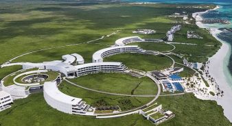 The St. Regis Kanai Resort, Riviera Maya - Aerial view of a large, modern beachfront resort complex with curved white buildings surrounded by greenery and ocean.