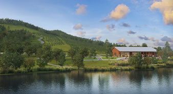 A modern barn-style building at Southall Farm & Inn - Franklin, TN sits near a reflective pond, surrounded by green hills, trees, and a winding road under a partly cloudy sky.