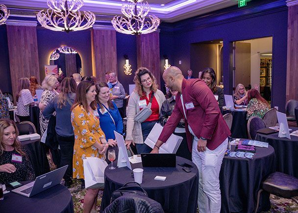 A group of people at a Retreats Resources Roadshow event, gathered around tables, engaging in conversation.